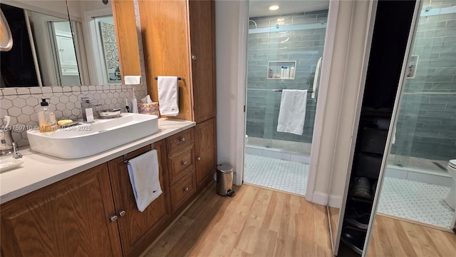 full bath with backsplash, a shower stall, toilet, and wood finished floors