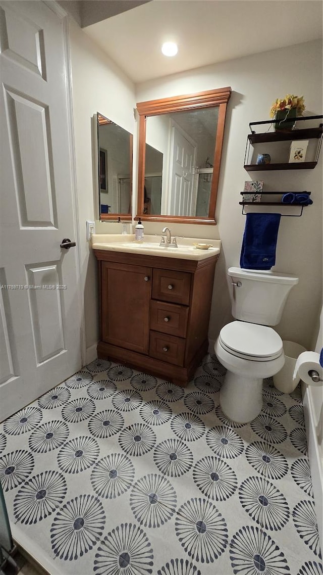 bathroom featuring toilet, vanity, and baseboards