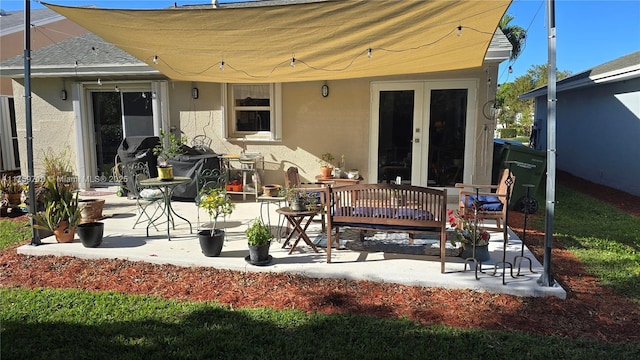 rear view of property with stucco siding, a patio, roof with shingles, and french doors