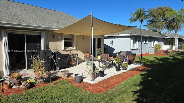 rear view of property featuring a shingled roof, stucco siding, central air condition unit, a patio area, and a lawn