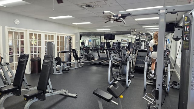 workout area with a paneled ceiling, visible vents, and ceiling fan