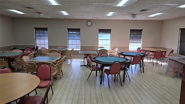 dining area with light wood-style flooring, visible vents, a drop ceiling, and ceiling fan