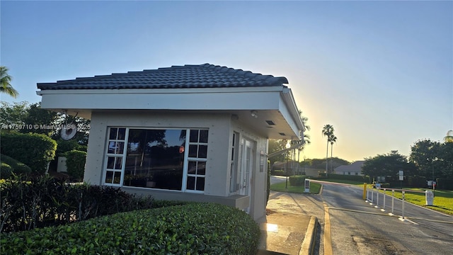 property exterior at dusk with stucco siding and a tile roof