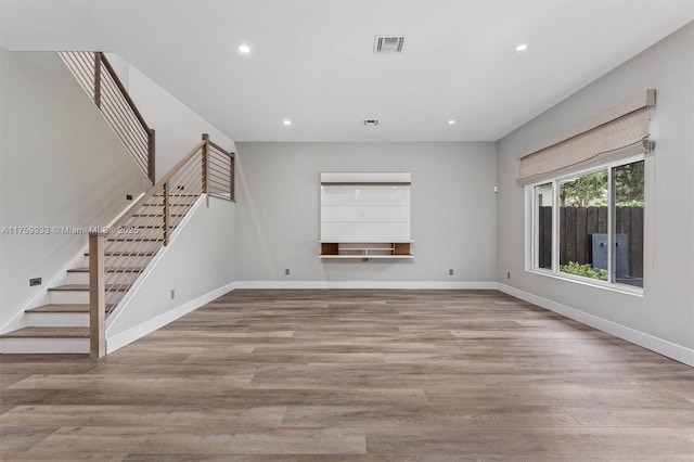 empty room featuring visible vents, wood finished floors, recessed lighting, baseboards, and stairs