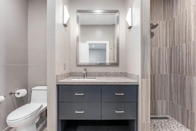 full bathroom with tiled shower, toilet, and vanity