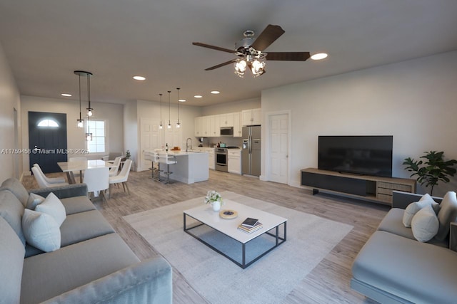 living area featuring a ceiling fan, recessed lighting, and light wood finished floors