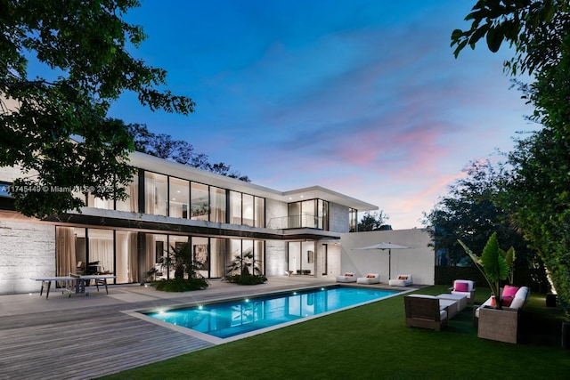 back of house featuring a yard, an outdoor pool, and a balcony