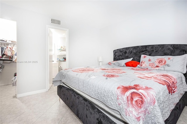 bedroom featuring light tile patterned floors, baseboards, visible vents, a closet, and a walk in closet