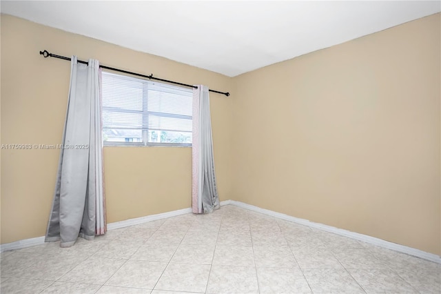 spare room with light tile patterned floors and baseboards