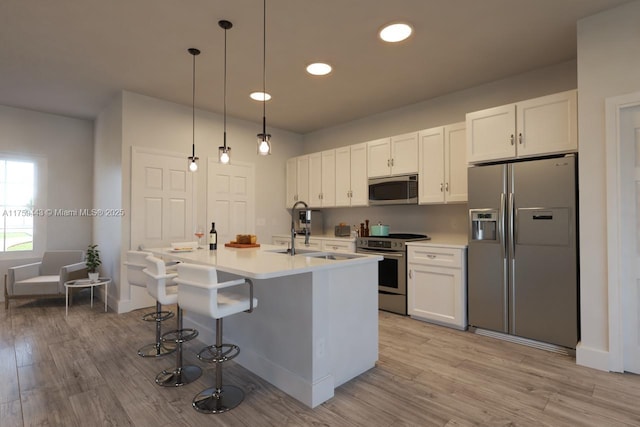 kitchen featuring white cabinets, appliances with stainless steel finishes, light countertops, and a sink