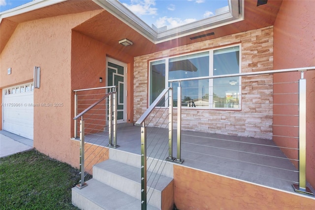 doorway to property featuring stone siding, stucco siding, and a garage