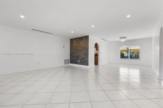 unfurnished living room featuring recessed lighting, light tile patterned floors, visible vents, and arched walkways