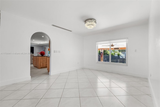 empty room featuring visible vents, recessed lighting, arched walkways, light tile patterned floors, and baseboards