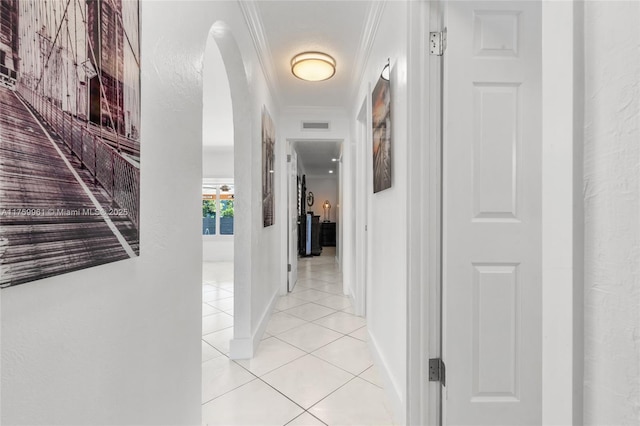 corridor with light tile patterned floors, visible vents, baseboards, and ornamental molding