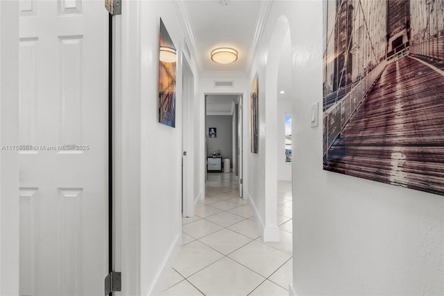 hallway with visible vents, baseboards, light tile patterned flooring, and crown molding