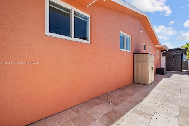 view of side of property featuring stucco siding and a patio area