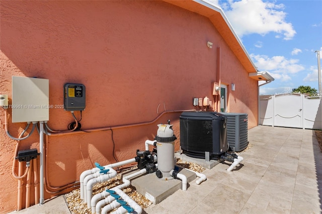 view of side of property featuring central air condition unit, stucco siding, and a gate