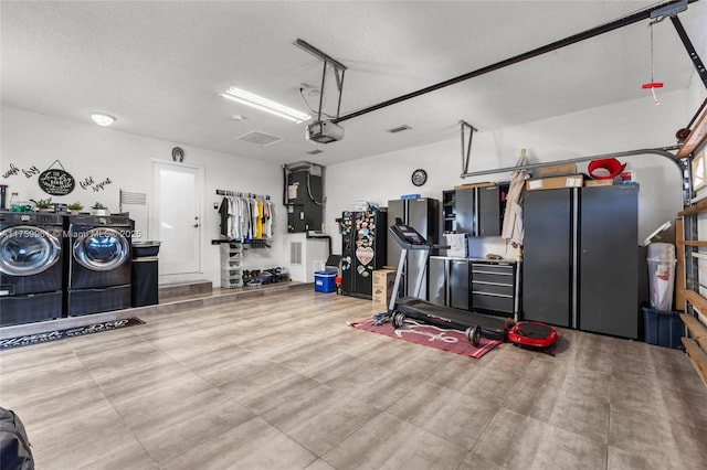 garage featuring heating unit, a garage door opener, and separate washer and dryer