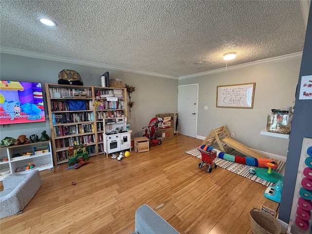 recreation room with a textured ceiling, wood finished floors, and ornamental molding