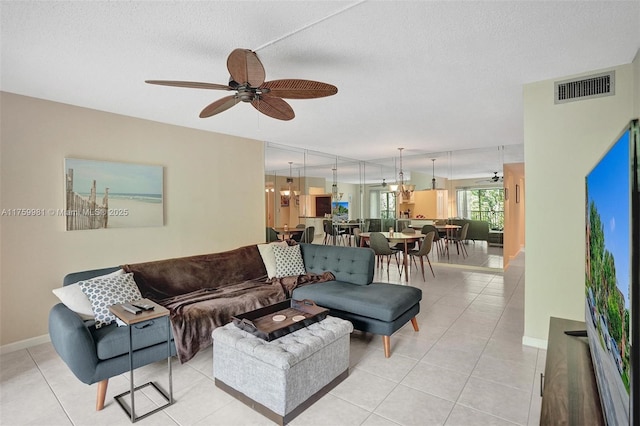 living area with light tile patterned flooring, a ceiling fan, visible vents, and a textured ceiling