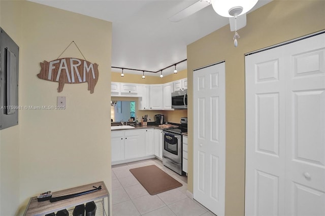 kitchen with a sink, dark countertops, stainless steel appliances, white cabinets, and light tile patterned flooring