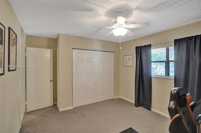 carpeted office space with a textured ceiling, baseboards, and ceiling fan