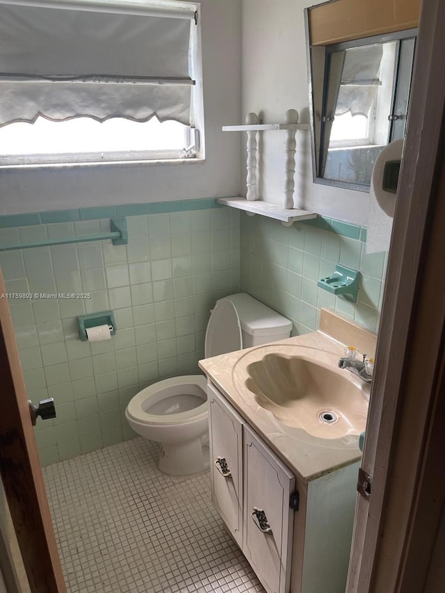 half bathroom with plenty of natural light, toilet, tile walls, and tile patterned flooring