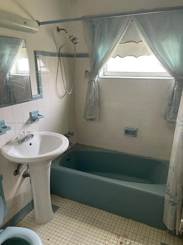 full bath with tile patterned floors, tile walls, tasteful backsplash, and shower / bath combo