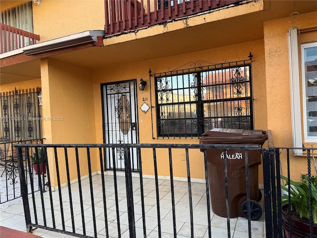 property entrance featuring a balcony and stucco siding