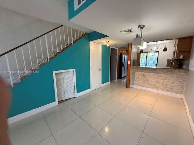 interior space featuring tile patterned floors, visible vents, baseboards, and stainless steel fridge with ice dispenser