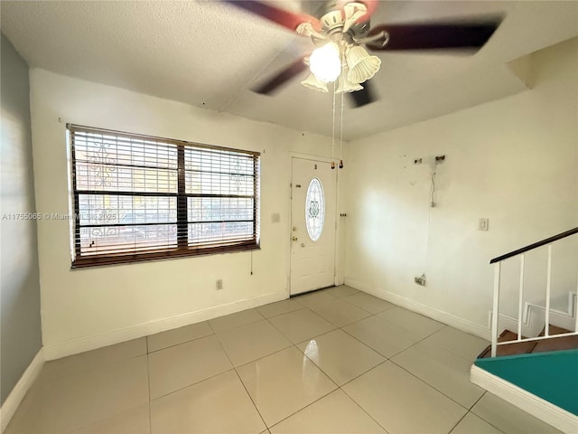 entryway featuring stairway, baseboards, a textured ceiling, and tile patterned flooring