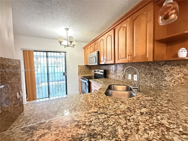 kitchen with a notable chandelier, a sink, tasteful backsplash, a textured ceiling, and stainless steel appliances