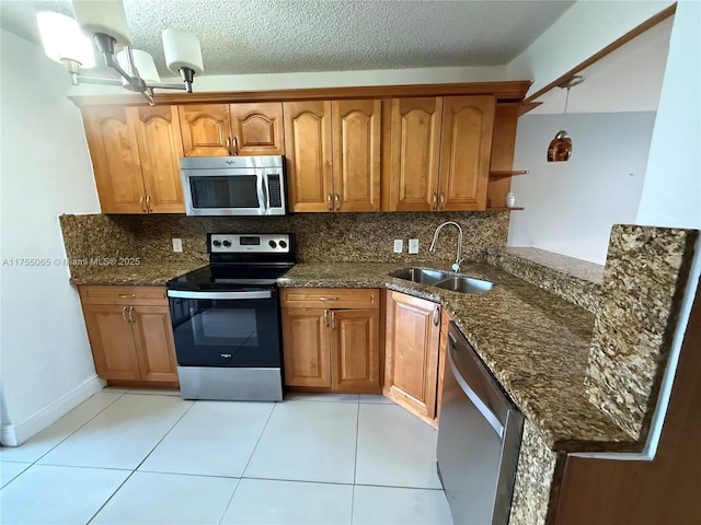 kitchen featuring tasteful backsplash, dark stone countertops, appliances with stainless steel finishes, and a sink