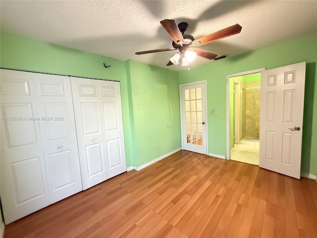 unfurnished bedroom featuring visible vents, light wood-style flooring, a textured ceiling, a closet, and baseboards