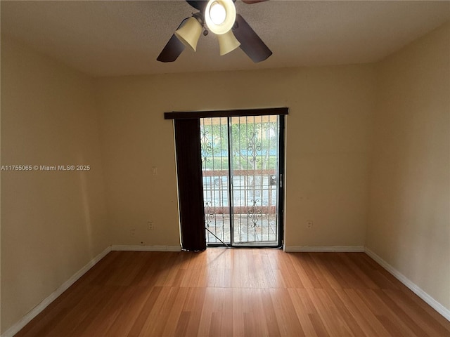 spare room featuring wood finished floors, baseboards, and ceiling fan