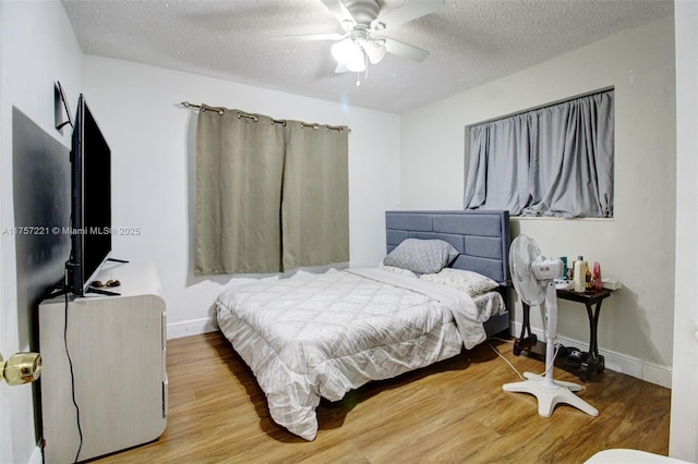 bedroom featuring a ceiling fan, wood finished floors, baseboards, and a textured ceiling