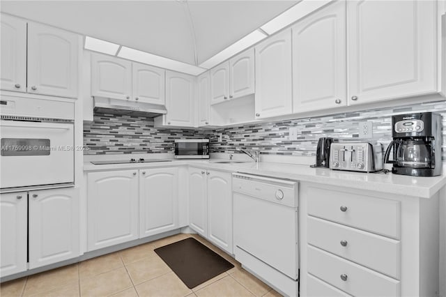 kitchen featuring under cabinet range hood, backsplash, white appliances, and light countertops