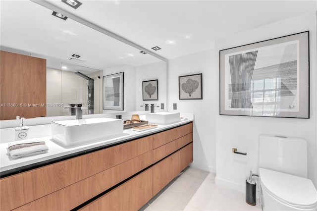 bathroom featuring double vanity, a stall shower, toilet, and a sink