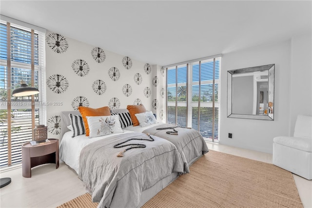 bedroom with wallpapered walls, a wall of windows, and an accent wall