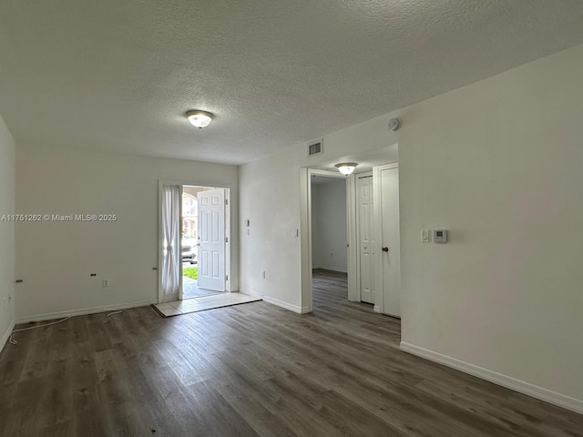 spare room featuring a textured ceiling, wood finished floors, visible vents, and baseboards