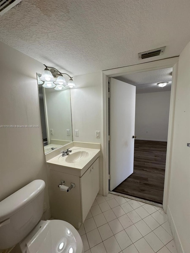 bathroom with vanity, visible vents, tile patterned flooring, a textured ceiling, and toilet