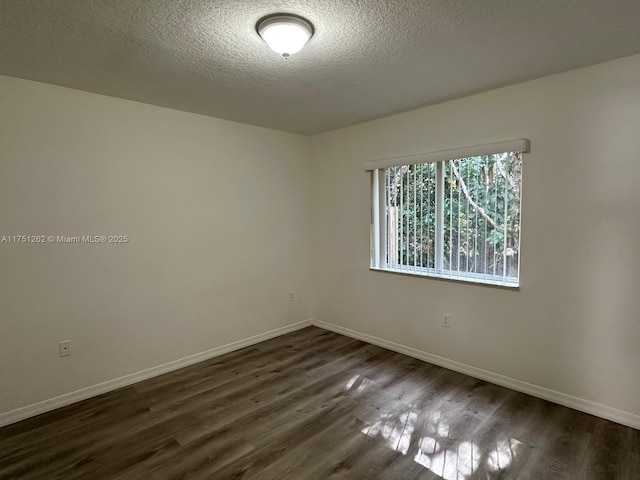 empty room featuring dark wood finished floors, baseboards, and a textured ceiling