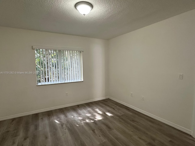 spare room featuring dark wood finished floors, baseboards, and a textured ceiling