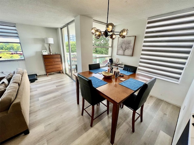 1351 NE Miami Gardens Dr Unit 325E, Miami, FL 33179 - dining space with light wood-style flooring, a textured ceiling, an inviting chandelier, and a healthy amount of sunlight