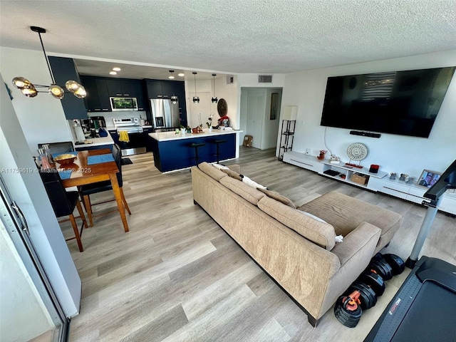 1351 NE Miami Gardens Dr Unit 325E, Miami, FL 33179 - living area with light wood-type flooring, visible vents, a textured ceiling, and an inviting chandelier