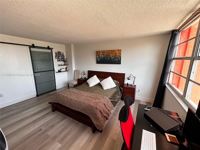 1351 NE Miami Gardens Dr Unit 325E, Miami, FL 33179 - bedroom with a barn door, baseboards, a textured ceiling, and wood finished floors