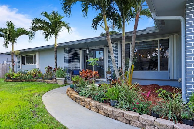 property entrance with a yard, brick siding, and stucco siding