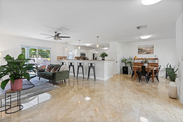 living room with visible vents, ceiling fan, and baseboards