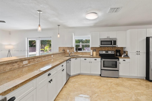 kitchen with tasteful backsplash, visible vents, appliances with stainless steel finishes, white cabinets, and a sink