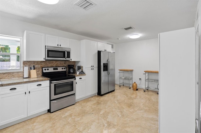 kitchen with stainless steel appliances, backsplash, visible vents, and white cabinets